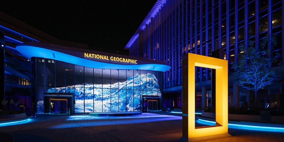 Le bâtiment du National Geographic de nuit, baigné de bleu sous son cadre jaune