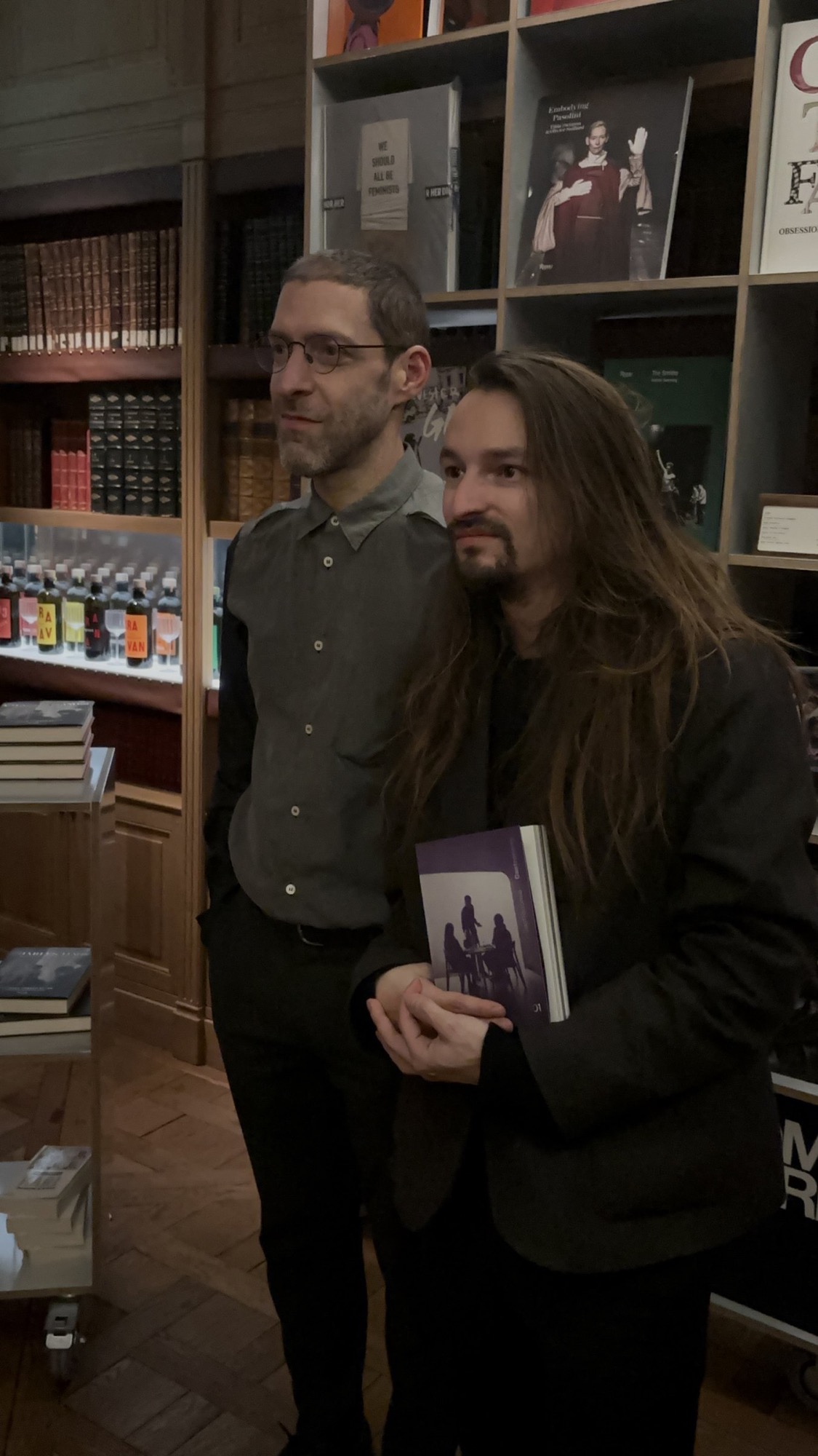 Le livre en main, près des rayonnages.